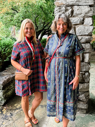Two women in matching blue dresses standing outdoors near a stone wall. Abby Plaid Mini Dress and Lettie Midi Dress