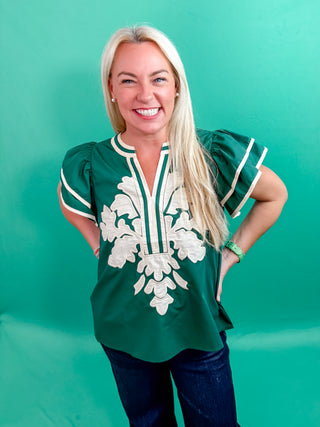 Solid flutter sleeve mutlicolor accent V-neck top featuring embroidered applique at front. Unlined. Woven. Non-sheer. Lightweight.