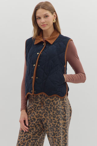 Solid sleeveless quilted corduroy quilted vest featuring contrast accent scallop hem and collar. Snap button front closure. Front pockets. Lined. Woven. Non-sheer. Lightweight.