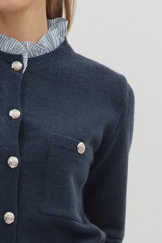 Solid long sleeve sweater knit cardigan featuring striped contrast ruffle details. Button front closure. Knit. Woven. Non-sheer. Lightweight.