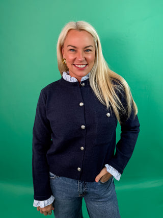 Solid long sleeve sweater knit cardigan featuring striped contrast ruffle details. Button front closure. Knit. Woven. Non-sheer. Lightweight.