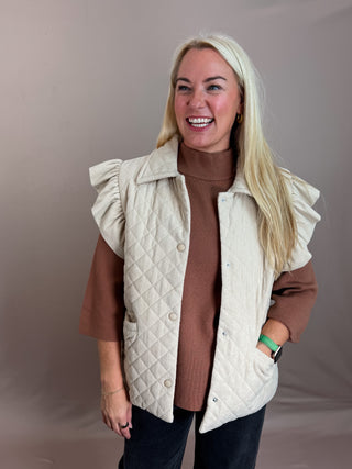 Corduroy Quilted Ruffle Sleeve Vest with Diamond quilt pattern, Ruffle cap sleeves, Front snap button closure, and Side slip pockets. Lined