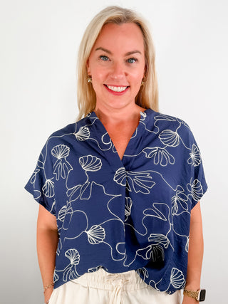 Embroidered navy blouse with floral design, v-neck cut, and oversized fit.
