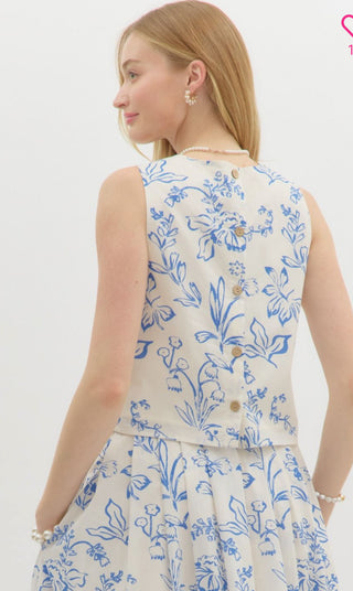 Floral print sleeveless waist-length top featuring wooden accent button back closure. Lined. Woven. Non-sheer. Lightweight.