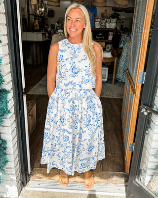 Floral print sleeveless waist-length top featuring wooden accent button back closure. Lined. Woven. Non-sheer. Lightweight.