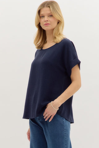 Navy Classic round neck short roll-up sleeve pullover top. Single button keyhole closure at back. Unlined. Woven. Non-sheer. Lightweight.