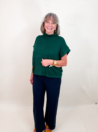 Solid short sleeve mock neck top featuring rolled cuffs. Unlined. Knit. Non-sheer. Lightweight.