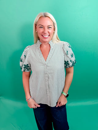 Stripe pattern V-neck ruffle band collar button front top featuring floral embroidered short bubble sleeve. Unlined. Woven. Non-sheer. Lightweight.