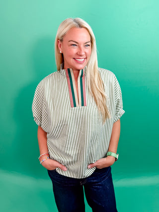 Stripe pattern high neck elasticated sleeve band dolman top featuring accented multicolor rib band split neck. Unlined. Woven. Non-sheer. Lightweight.