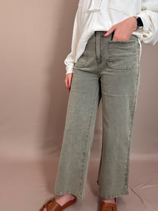 Solid high waisted wide leg ankle length pants featuring patch pockets at front. Faux pocket at back. Belt loops. Button and zipper closure at front. Unlined. Woven. Non-sheer. Lightweight.