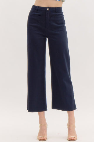 Solid high waisted wide leg ankle length pants featuring patch pockets at front. Faux pocket at back. Belt loops. Button and zipper closure at front. Unlined. Woven. Non-sheer. Lightweight.
