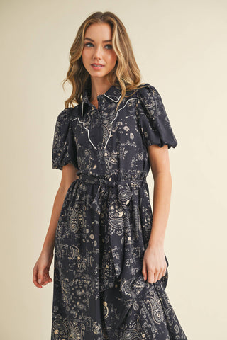 This midi shirt dress features an allover paisley print, contrast piping detail, puff sleeves and complete with a waist tie.