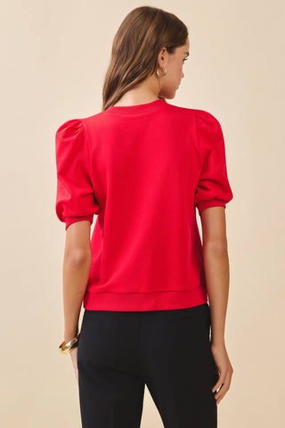 A red knit top featuring a crew neckline, short puff sleeves with gathered shoulders, and ribbed cuffs and hem for a polished fit.