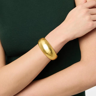 A gold wide, gracefully tapering bangle with a rounded profile and hand-hammered finish, featuring an opulent geometric piercework interior.