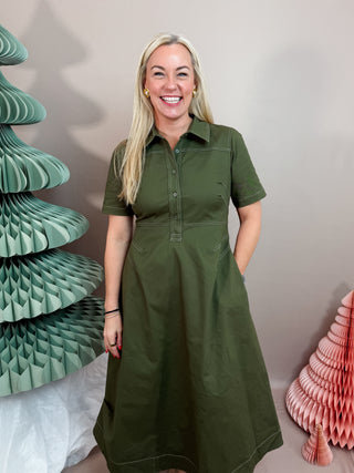 A midi dress featuring contrast stitching throughout. Designed with a collared neckline, short sleeves, and a partial button placket at the front. The fitted bodice defines the waist before falling into an A-line skirt with a subtle flare.