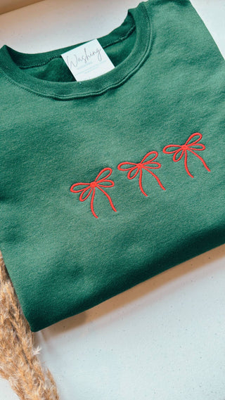 Green Christmas sweatshirt with embroidered red bows.