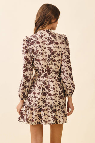 A floral mini dress featuring a high neckline and long puff sleeves with gathered cuffs. Designed with a front button closure and a removable buckle belt to cinch the waist. Finished with a tiered ruffle hem for a feminine, playful touch.