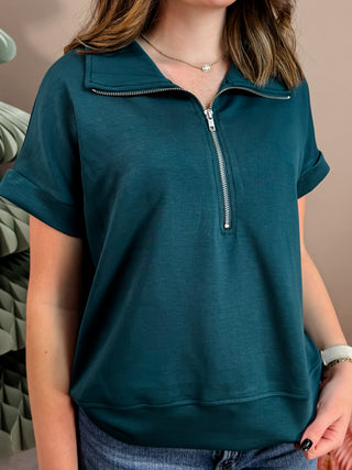 Blue short sleeve top with fold down collar, quarter zip, and easygoing fit