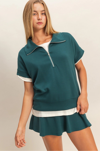 Blue short sleeve top with fold down collar, quarter zip, and easygoing fit