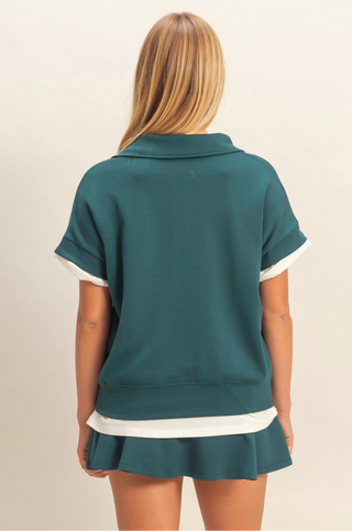 Blue short sleeve top with fold down collar, quarter zip, and easygoing fit