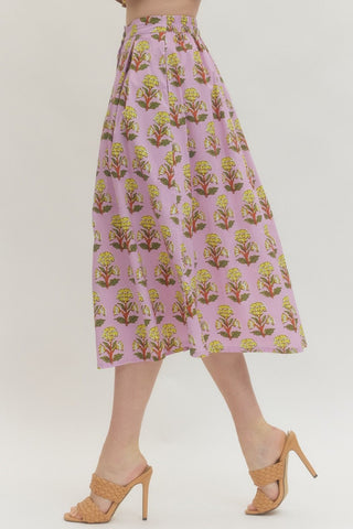 Floral print midi skirt featuring front button closure with gathered waist. Elastic at back waist. Side pockets. Lined. Woven. Non-sheer. Lightweight.