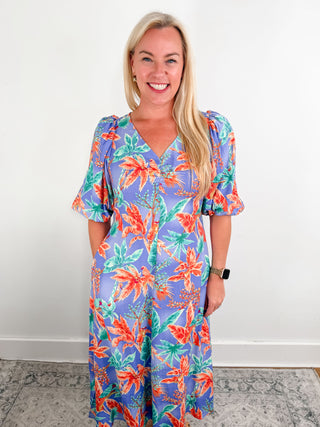 A tropical midi dress with pockets, balloon sleeves, a tie back, and v-neck cut. 