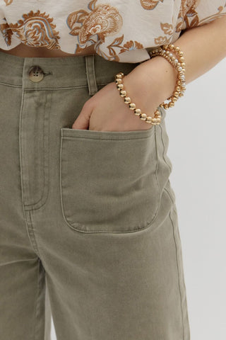 Solid high waisted wide leg ankle length pants featuring patch pockets at front. Faux pocket at back. Belt loops. Button and zipper closure at front. Unlined. Woven. Non-sheer. Lightweight.
