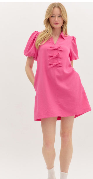 Solid short bubble sleeve pullover mini dress featuring bow accent below spread neck collar. Pockets at sides. Lined. Woven. Non-sheer. Lightweight